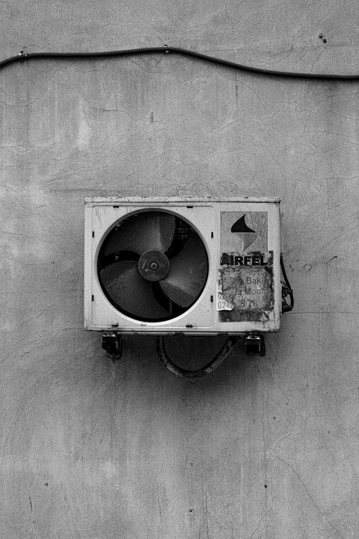 Black and white photo of a vintage air conditioning unit mounted on a concrete wall.